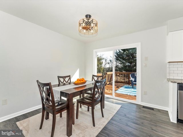 dining area featuring dark wood-type flooring and an inviting chandelier