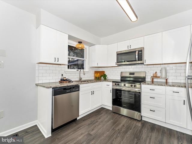 kitchen featuring dark stone countertops, appliances with stainless steel finishes, sink, and white cabinets