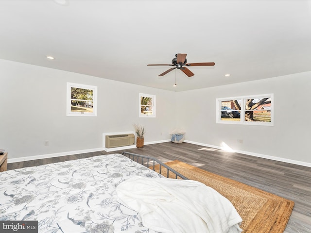 bedroom featuring ceiling fan, wood-type flooring, and an AC wall unit