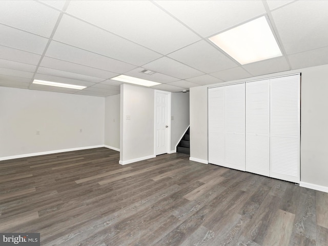 basement with a paneled ceiling and dark hardwood / wood-style floors