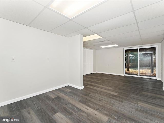 empty room with a drop ceiling and dark wood-type flooring