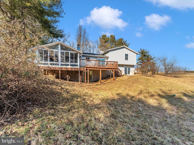 back of property with a sunroom, a deck, and a lawn