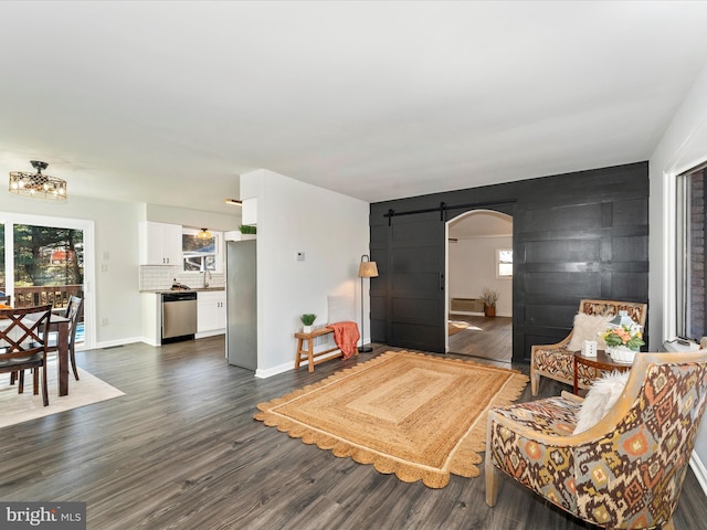 living room featuring a barn door, an inviting chandelier, and dark hardwood / wood-style flooring