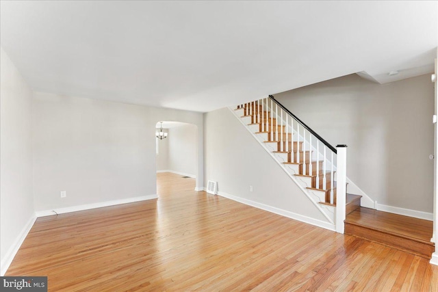 unfurnished living room with light hardwood / wood-style floors and a notable chandelier