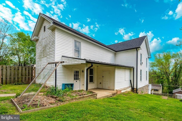 back of house with fence, a yard, and a vegetable garden