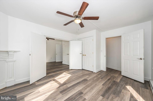 unfurnished bedroom with baseboards, baseboard heating, wood finished floors, and ceiling fan