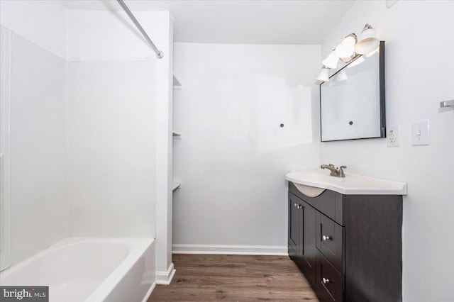 bathroom featuring wood finished floors, vanity,  shower combination, and baseboards