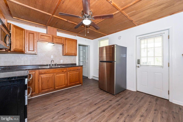 kitchen featuring tasteful backsplash, wood ceiling, appliances with stainless steel finishes, dark countertops, and a sink