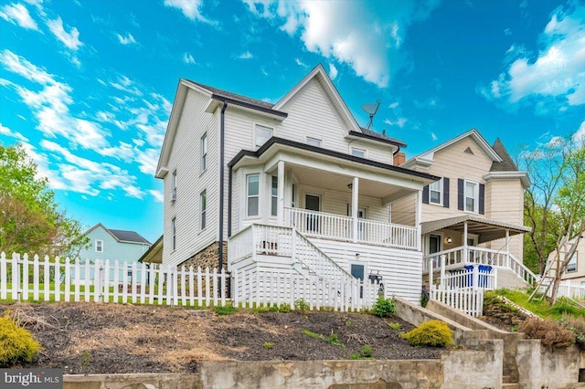 view of front of property featuring stairway, a porch, and fence