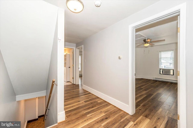 corridor with an upstairs landing, a baseboard radiator, wood finished floors, and baseboards