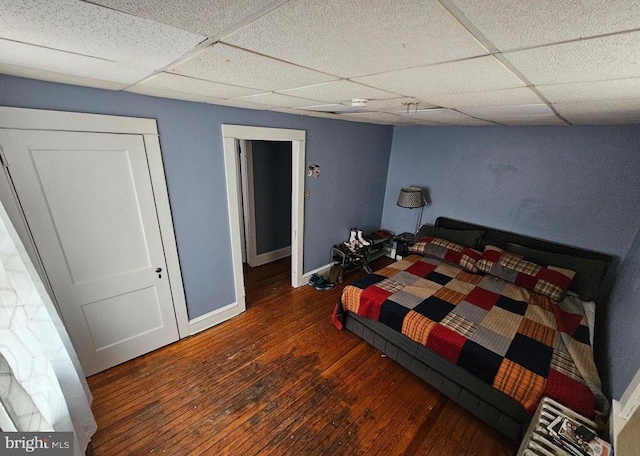 bedroom with a paneled ceiling and dark hardwood / wood-style flooring