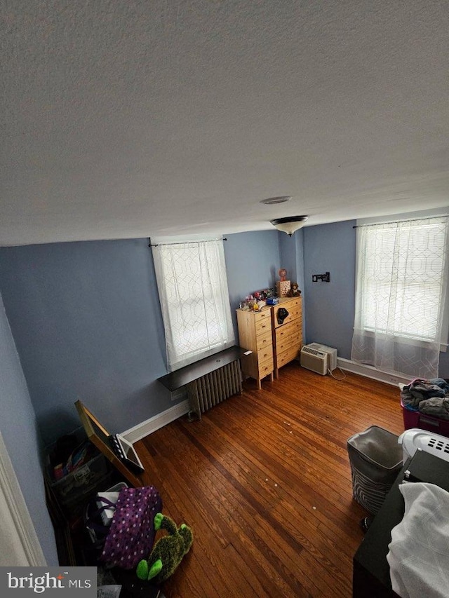 bedroom with multiple windows, hardwood / wood-style floors, and a textured ceiling