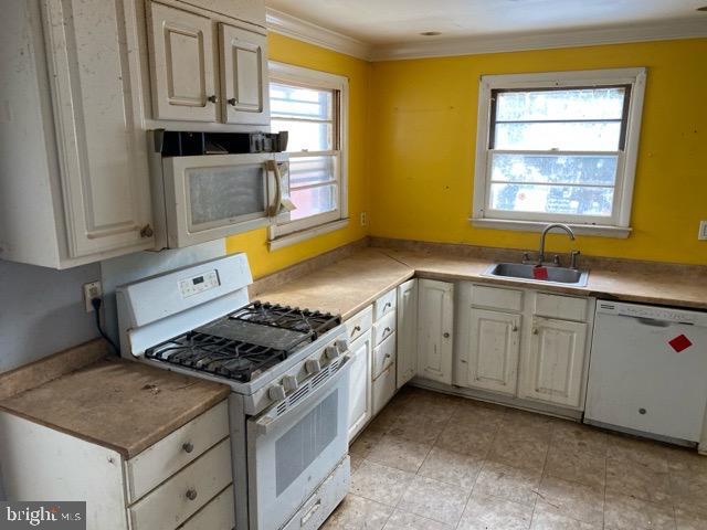 kitchen with crown molding, sink, and white appliances