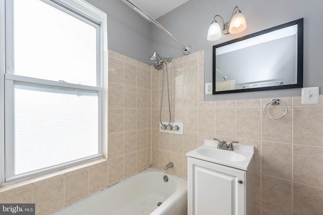 bathroom featuring vanity, tiled shower / bath, and tile walls