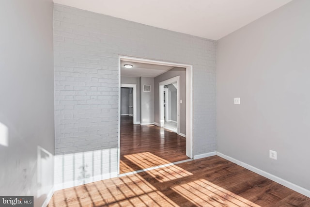 corridor featuring dark hardwood / wood-style flooring and brick wall