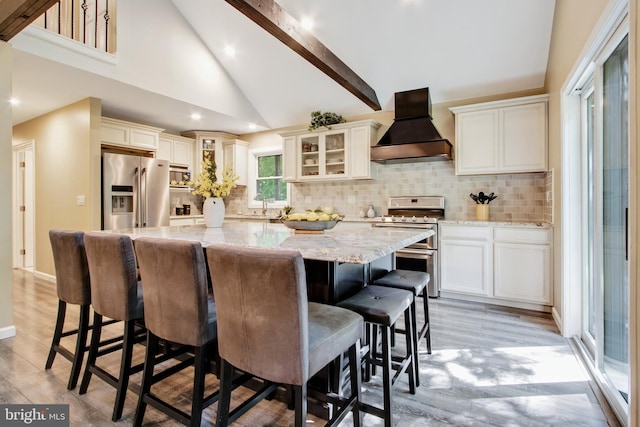 kitchen with light stone counters, a center island, a kitchen breakfast bar, custom range hood, and stainless steel appliances