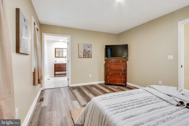 bedroom featuring connected bathroom and hardwood / wood-style flooring