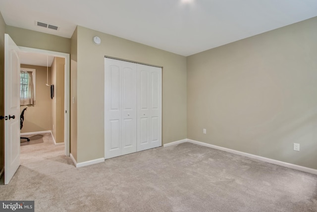 unfurnished bedroom featuring light colored carpet and a closet