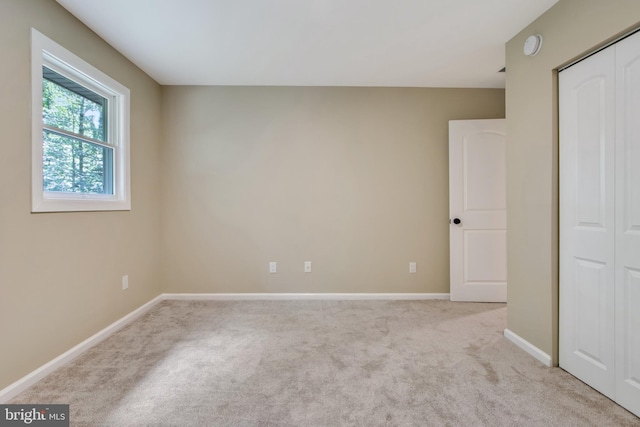 unfurnished bedroom featuring light colored carpet and a closet