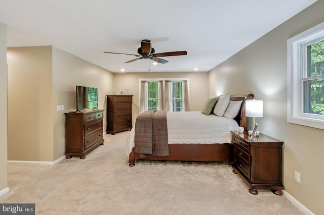 bedroom with ceiling fan, light carpet, and multiple windows