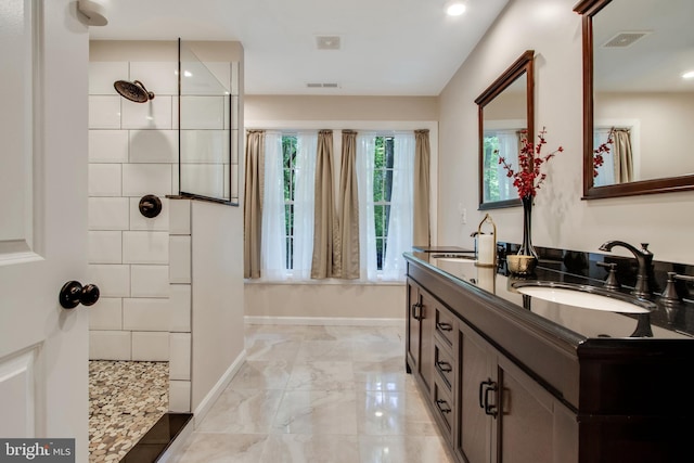 bathroom with tiled shower and vanity