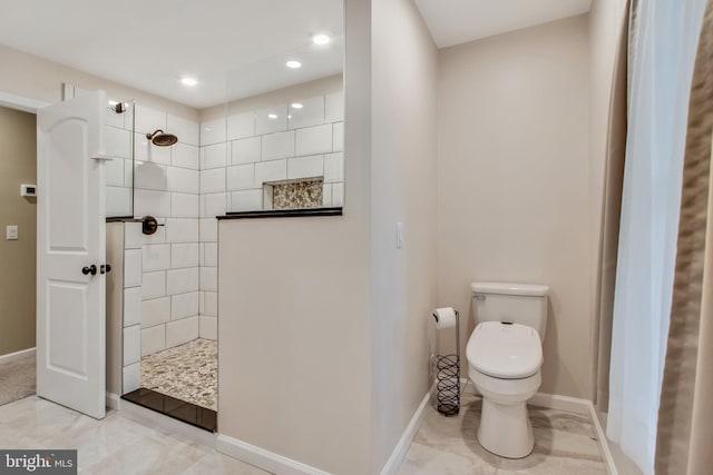 bathroom with a tile shower and toilet