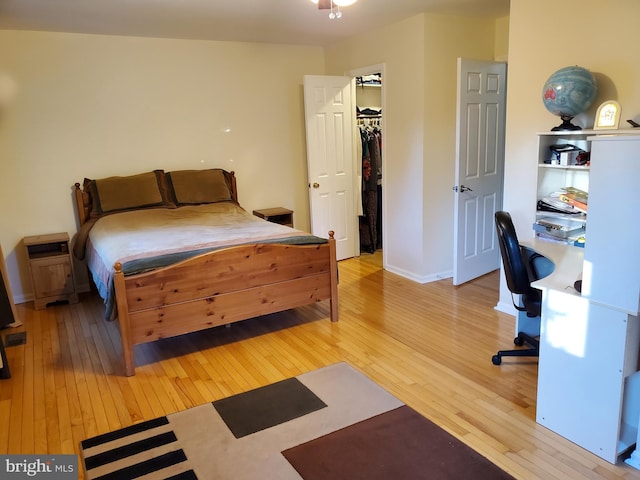 bedroom with a spacious closet, hardwood / wood-style floors, and a closet