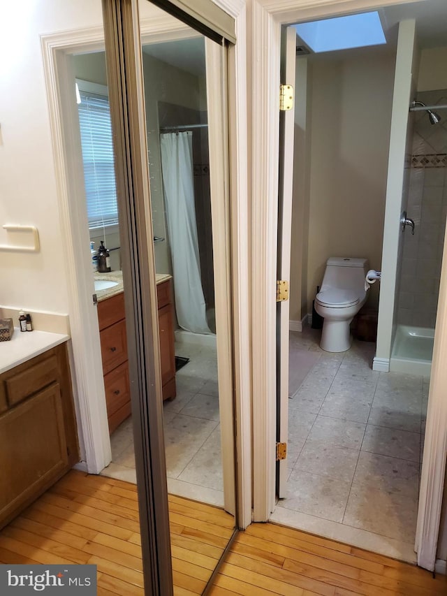 bathroom featuring vanity, wood-type flooring, toilet, and walk in shower