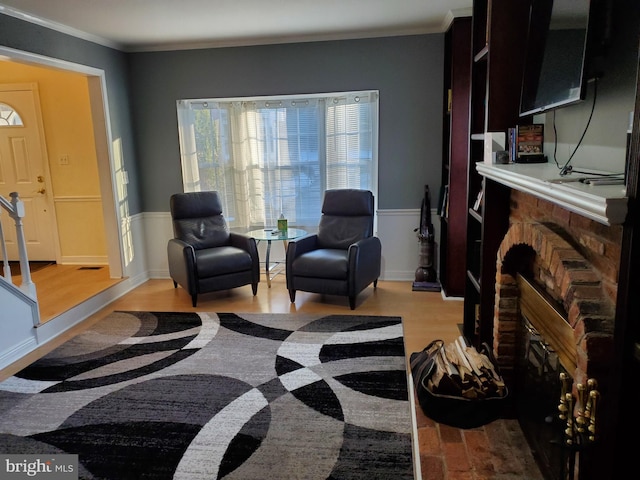 living area with a fireplace, ornamental molding, and light hardwood / wood-style floors