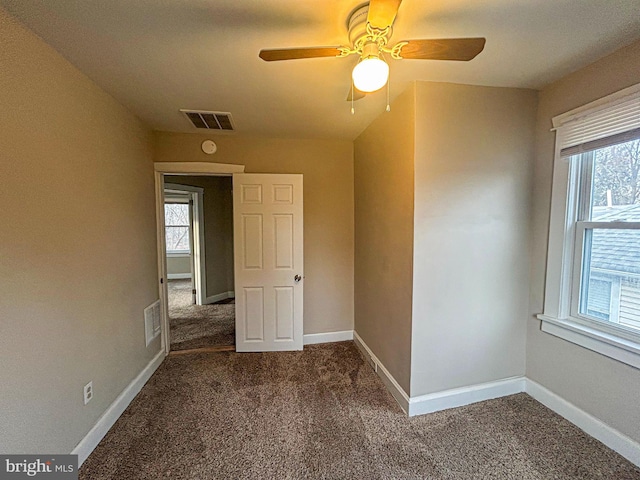 unfurnished room featuring ceiling fan and dark colored carpet