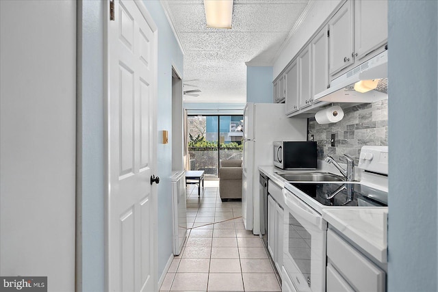 kitchen with sink, a textured ceiling, light tile patterned floors, appliances with stainless steel finishes, and decorative backsplash