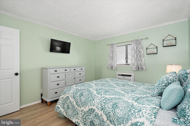 bedroom featuring ornamental molding, a wall unit AC, and light hardwood / wood-style flooring