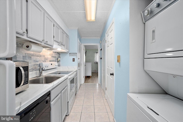 kitchen featuring dishwasher, white range with electric cooktop, stacked washer / dryer, tasteful backsplash, and light tile patterned flooring