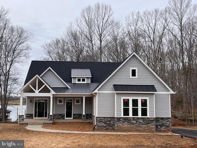 craftsman house with metal roof, a standing seam roof, stone siding, and covered porch