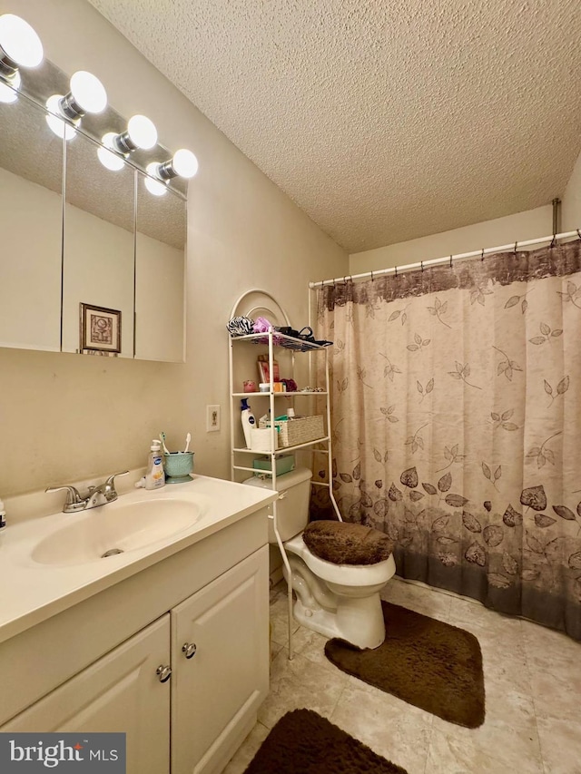 bathroom featuring toilet, vanity, a textured ceiling, and tile patterned floors