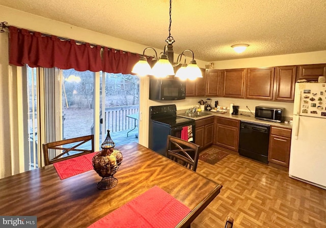 kitchen featuring a textured ceiling, black appliances, pendant lighting, sink, and light parquet floors