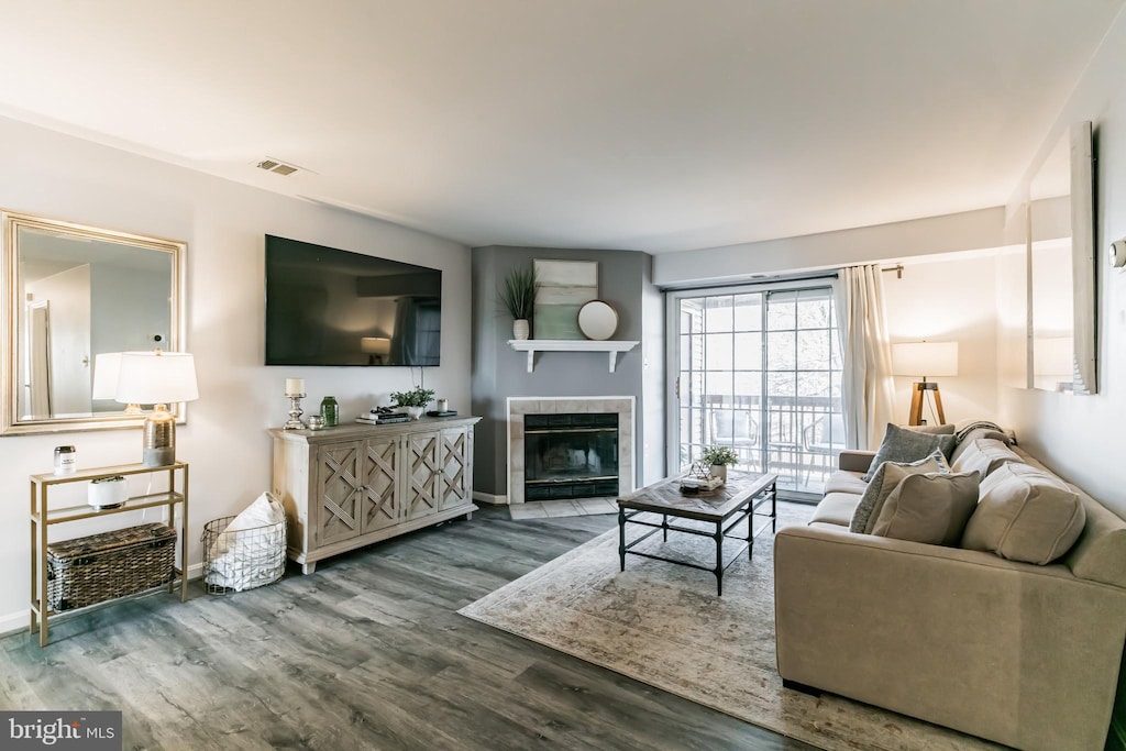 living room with a tiled fireplace and hardwood / wood-style floors