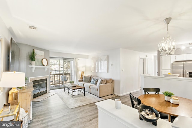 living room with an inviting chandelier, a fireplace, and light hardwood / wood-style flooring