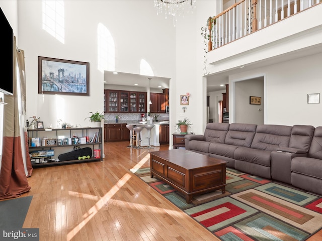 living room with a towering ceiling, hardwood / wood-style floors, and a chandelier