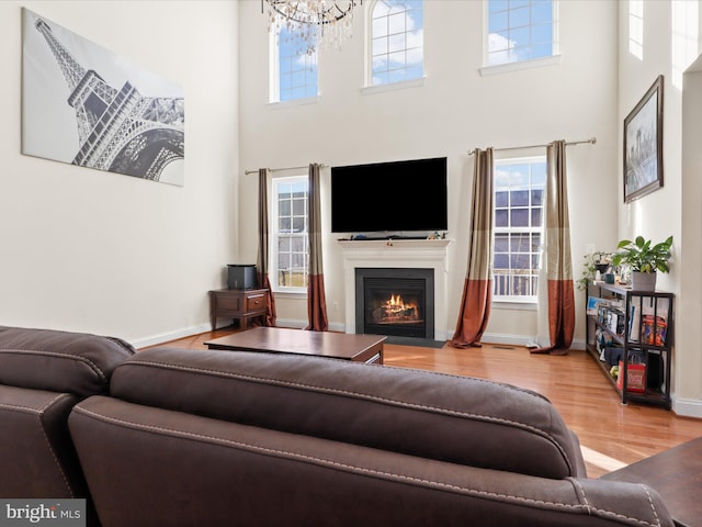 living room featuring an inviting chandelier, wood-type flooring, a high ceiling, and plenty of natural light