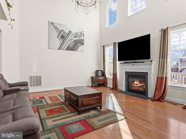 living room with a chandelier, hardwood / wood-style floors, and a high ceiling