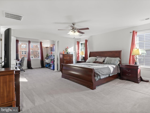 bedroom featuring ceiling fan, light colored carpet, and ornate columns