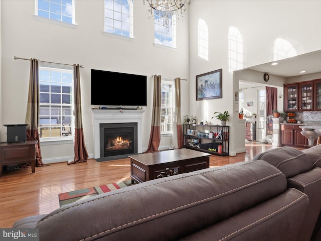 living room featuring an inviting chandelier, a wealth of natural light, and light wood-type flooring