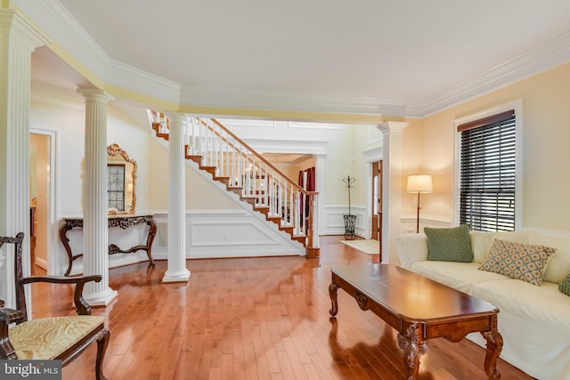 living room with hardwood / wood-style flooring, crown molding, and ornate columns