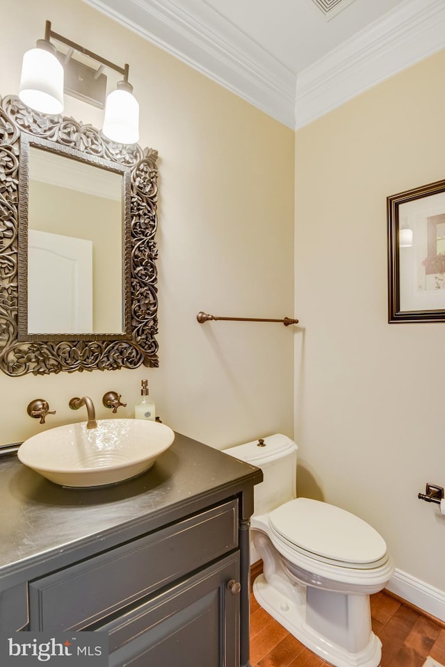 bathroom with crown molding, wood-type flooring, toilet, and vanity