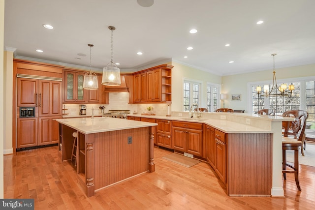 kitchen with decorative light fixtures, a breakfast bar, sink, and kitchen peninsula