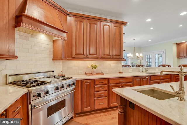 kitchen with sink, stainless steel range, hanging light fixtures, and premium range hood