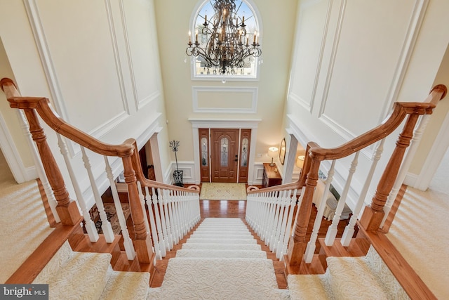 foyer featuring a towering ceiling, a notable chandelier, and light wood-type flooring