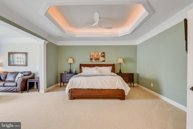 carpeted bedroom featuring ceiling fan, ornamental molding, a tray ceiling, and decorative columns