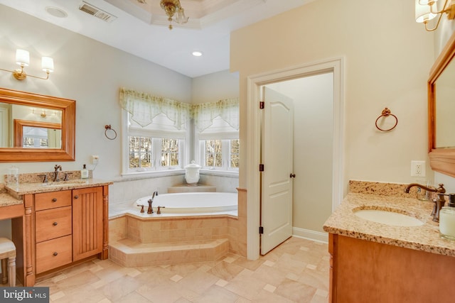 bathroom with vanity, tiled bath, and a raised ceiling